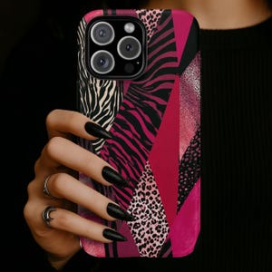 May include: A phone case with a vibrant geometric design featuring zebra stripes, leopard spots, and solid pink panels. The case has a glossy finish and a black camera module.