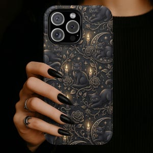 May include: Black phone case featuring a repeating pattern of black cats, candles, roses, and crescent moons. The case has a dark, gothic aesthetic with intricate details and a matte finish. The case has a camera cutout.