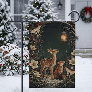 May include: A rectangular garden flag featuring a dark forest scene with a fawn and a fox sitting together. The scene is framed by white flowers, red berries, and two moths. A glowing lantern hangs from a branch above the animals in the dark woods.