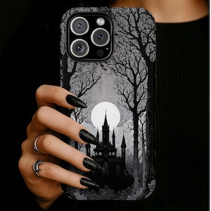 May include: A black smartphone case featuring a detailed monochromatic illustration of a dark castle silhouette set against a large, bright full moon. The design includes intricate line work depicting a dense forest of tall, leafless trees.