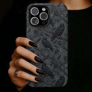 May include: A dark gray phone case featuring a repeating pattern of black ravens perched on branches with roses and crescent moons. The case has a matte finish and a camera cutout.