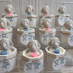 May include: A collection of white ceramic candle holders with elephant-shaped candles. Each holder features a small tag with two elephants and the text "Forever & Always".