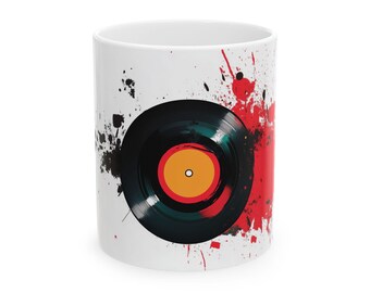 May include: White ceramic mug with a black vinyl record design. The record has a red and orange center and is surrounded by red and black paint splatters.