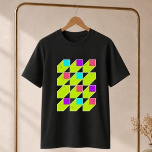 Könnte beinhalten: Ein schwarzes Kurzarm-T-Shirt mit einem zentralen Grafikdruck in einem Gittermuster. Das Design besteht aus lindgrünen geometrischen Formen mit einer abgenutzten Textur, akzentuiert durch kleine, einfarbige Quadrate in leuchtendem Pink, Lila und Cyanblau.