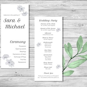 May include: Wedding ceremony program with white flowers and green leaves on a woodgrain background. The program lists the order of events for the ceremony and the wedding party.
