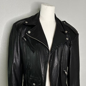 May include: A black leather motorcycle jacket with a zipper closure, two front pockets, and a belt with silver studs.