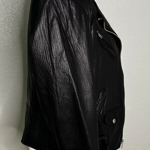 May include: A black leather motorcycle jacket with a zipper closure and a belt at the waist.