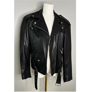May include: A black leather motorcycle jacket with a zipper closure and multiple pockets. The jacket has a silver zipper and silver hardware.