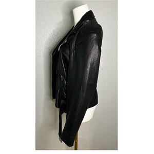 May include: A black leather motorcycle jacket with a zipper closure and a belt at the waist.