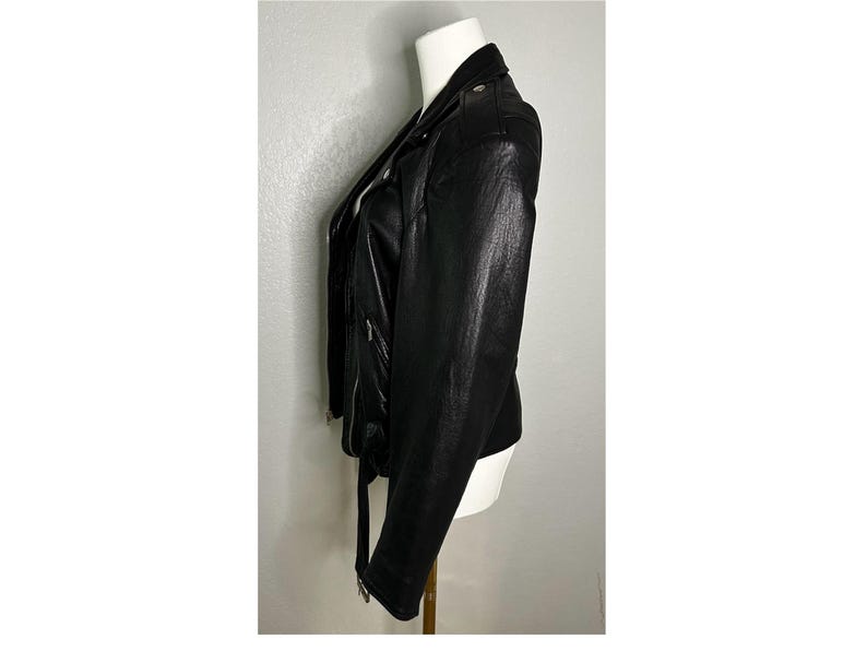 May include: A black leather motorcycle jacket with a zipper closure and a belt at the waist.
