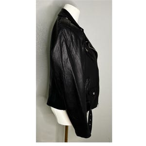 May include: A black leather motorcycle jacket with a zipper closure and a belt at the waist.