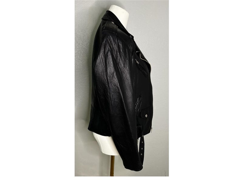 May include: A black leather motorcycle jacket with a zipper closure and a belt at the waist.