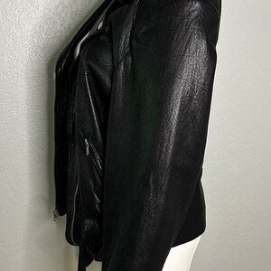 May include: A black leather motorcycle jacket with a zipper closure and a belt at the waist.