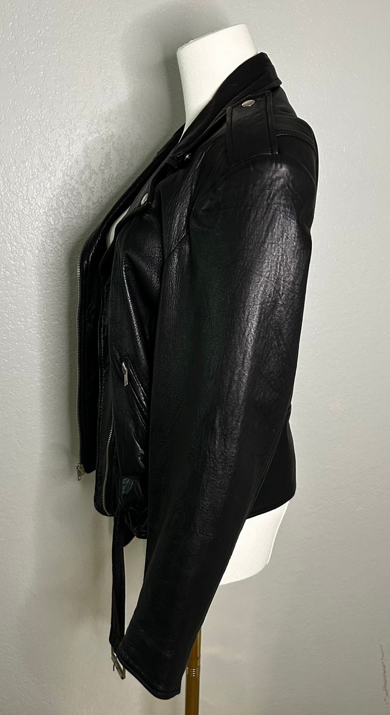 May include: A black leather motorcycle jacket with a zipper closure and a belt at the waist.