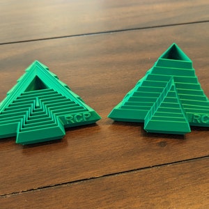 May include: Two green plastic pyramid-shaped objects with a maze-like design and the letters "RCP" printed on the bottom.