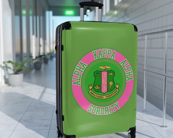 Niedlicher Alpha Kappa Sorority-Koffer – auch bekannt als rosa und grüner Soror-Reisekoffer mit griechischen Buchstaben und rundem Design.