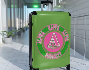 Niedlicher Alpha Kappa Sorority-Koffer – auch bekannt als rosa und grüner Soror-Reisekoffer mit griechischen Buchstaben und rundem Design.