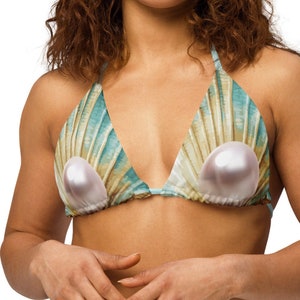 May include: A turquoise and gold bikini top with a seashell design and two large pearl accents.
