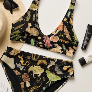 May include: Black bikini top and bottom with a nature-inspired print featuring mushrooms, butterflies, and other woodland creatures. The print is on a black background with gold accents.