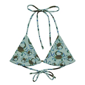 May include: A light blue triangle bikini top with a crab print. The top has adjustable straps and ties at the back.