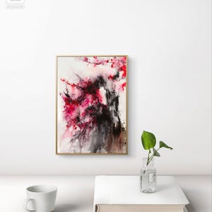 以下が含まれることがあります： 赤、黒、白の色合いの抽象的な水彩画。絵画の中央には大きな抽象的な形があり、その周りを小さな形と線が囲んでいます。絵画は金色の額縁に入っています。