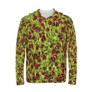 Puede incluir: Una sudadera con capucha de manga larga con un estampado de plantas carnívoras rojas y verdes. Las plantas tienen la boca abierta y dientes afilados.