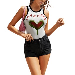 May include: A white sleeveless tank top with black trim around the neckline and armholes. The front features a graphic of a red and green Venus flytrap shaped like a heart, with the text LOVE BITES arched in red letters above the plant.