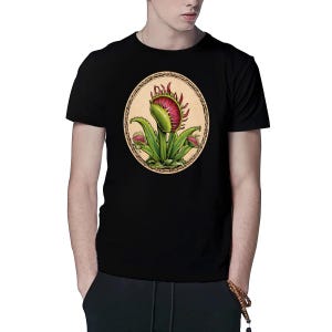May include: Black t-shirt featuring a graphic of a green carnivorous plant with red flowers in a circle on the front.