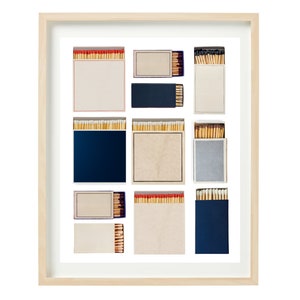 May include: A framed print of a collection of matchboxes arranged in a grid pattern. The matchboxes are various colors, including blue, gray, and white. Some of the matchboxes have red and white matchsticks visible.