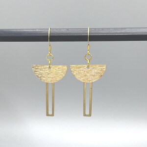May include: Gold earrings with a textured half-circle design and a straight bar hanging below.