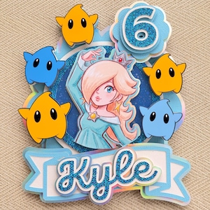 May include: A white ceramic mug with a black handle and the text "But First, Coffee" in a black, handwritten-style font. The mug is on a white surface.