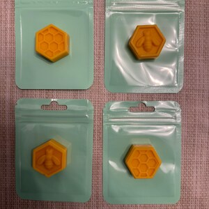 Puede incluir: Cuatro bolsas de plástico transparentes con cremalleras resellables, cada una contiene una pequeña fusión de cera amarilla de forma hexagonal. Dos de las fusiones presentan un patrón de panal, mientras que las otras dos presentan un diseño de abeja.