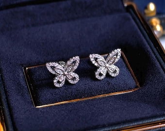 May include: A pair of silver butterfly earrings with clear cubic zirconia stones. The earrings are displayed in a black velvet box.