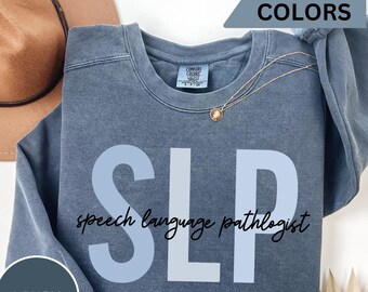 May include: A blue denim sweatshirt with the text "SLP speech language pathologist" printed in white on the front. The sweatshirt is a comfortable, casual style.