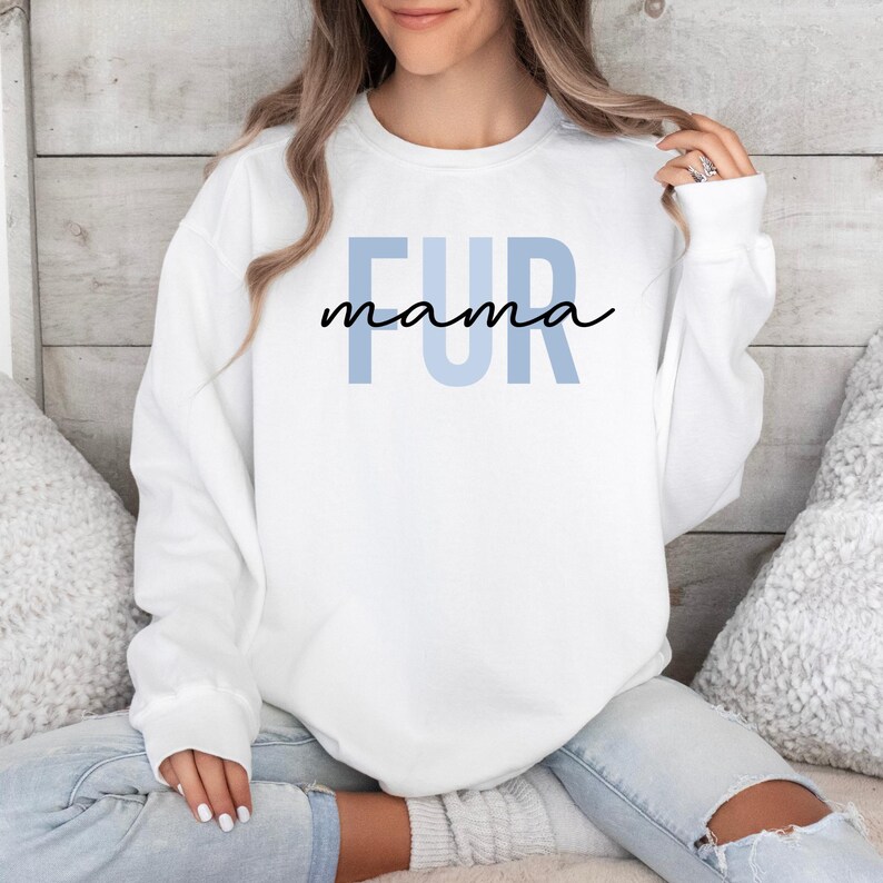 May include: White sweatshirt with the text "FUR mama" in blue and black lettering.