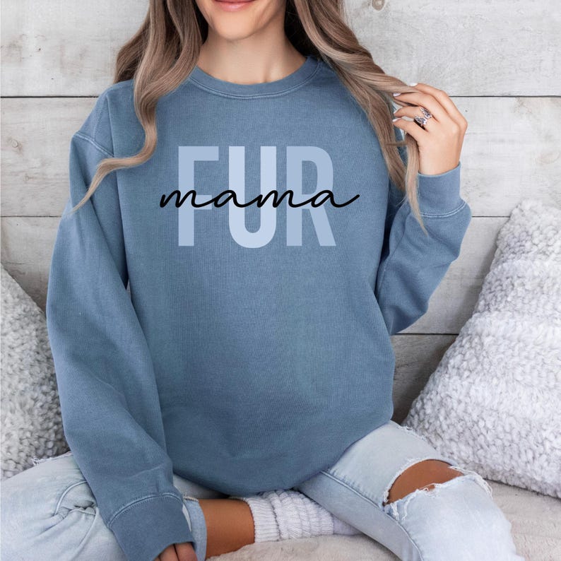 May include: A light blue sweatshirt with the text "FUR mama" printed on the front.