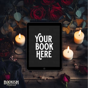 Può includere: Un tablet digitale con il testo "YOUR BOOK HERE" su uno schermo nero, circondato da rose rosse, candele accese e verde su una superficie di legno rustico. La scena evoca un'atmosfera accogliente e romantica.