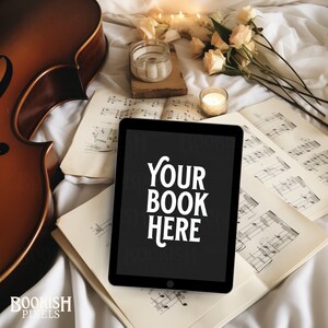 Könnte beinhalten: Ein schwarzes Tablet-Computer mit dem Text "YOUR BOOK HERE" auf dem Bildschirm. Das Tablet liegt auf einer weißen Oberfläche mit Notenblättern und einem Cello im Hintergrund.