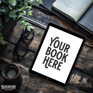 May include: A black tablet computer with a white screen displaying the text "YOUR BOOK HERE" on a rustic wooden surface with a cup of coffee and a pair of glasses.