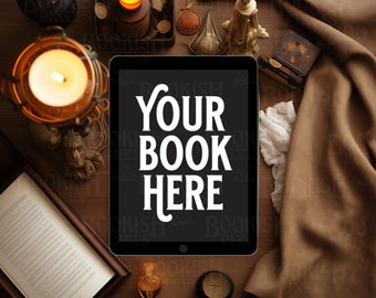 May include: A black tablet with a white screen displaying the text "YOUR BOOK HERE" on a wooden table with candles, decorative items, and a brown fabric.