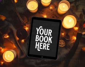 May include: An overhead shot features a tablet with the text "YOUR BOOK HERE" on the screen, surrounded by lit candles in glass holders, fairy lights, and dried flowers. The scene is set on a wooden surface with a dark, moody aesthetic.