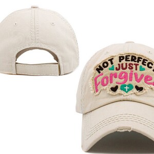 May include: Beige baseball cap with a distressed look and an embroidered patch that reads "Not Perfect Just Forgiven" with hearts and a cross.