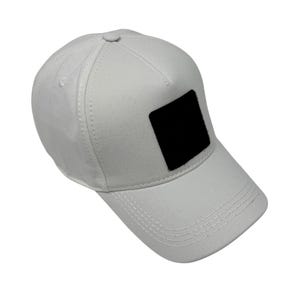 Puede incluir: Gorra de b&eacute;isbol blanca con visera curva y parche cuadrado negro en la parte delantera. La gorra tiene un dise&ntilde;o estructurado con costuras visibles y un bot&oacute;n en la parte superior. Fabricada en tejido duradero.