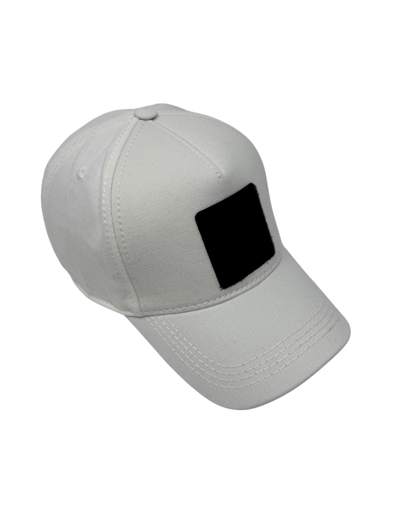 Puede incluir: Gorra de b&eacute;isbol blanca con visera curva y parche cuadrado negro en la parte delantera. La gorra tiene un dise&ntilde;o estructurado con costuras visibles y un bot&oacute;n en la parte superior. Fabricada en tejido duradero.