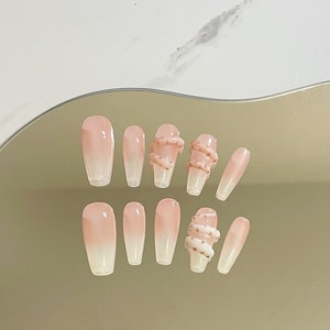 May include: Set of ten long, oval-shaped, ombre pink and white press-on nails with a snake design on two of the nails.