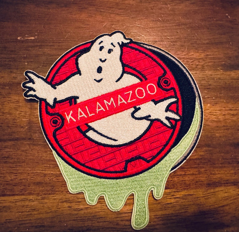 Peut inclure: Un patch brod&eacute; rouge et blanc repr&eacute;sentant un fant&ocirc;me avec une banni&egrave;re rouge "KALAMAZOO" sur son corps. Le fant&ocirc;me &eacute;merge d'une grille d'&eacute;gout rouge et noire avec de la bave verte qui coule des bords.