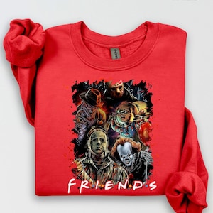 以下が含まれることがあります： ホラー映画のキャラクターのグラフィックが特徴の赤いスウェットシャツ。デザインには、マイケル・マイヤーズ、ペニーワイズ、チャッキーの画像が含まれており、白いスクリプトで「FRIENDS」という言葉が書かれています。「Red」という言葉が右上隅に印刷されています。