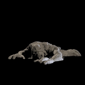 May include: A grey, sculpted figure of a creature with a menacing expression, lying on its stomach with its arms outstretched. The creature has a large head with sharp teeth and a furrowed brow.