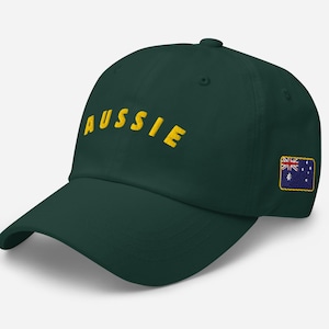 Op de afbeelding: Een donkergroene baseballpet met het woord "Aussie" in het geel geborduurd op de voorkant. De pet heeft ook een klein Australisch vlagpatch aan de zijkant.