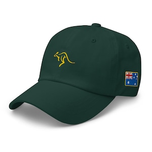 May include: A dark green baseball cap with a curved brim. The cap features a gold embroidered kangaroo on the front and an Australian flag patch on the side. The hat is made of a soft material.